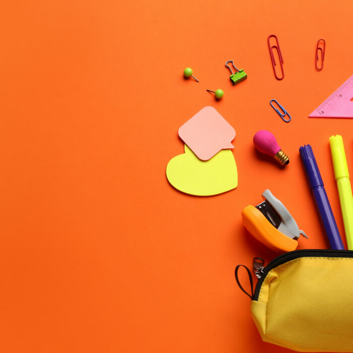 Pencil case with school stationery on orange background, top view